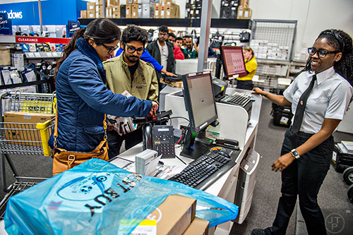 Isha Arora (left) and Abhijeed Srivastava pay for their purchases with the help of Brittaney Traylor inside Best Buy Perimeter in Atlanta during Gray Thursday on Thanksgiving night, Thursday, November 26, 2015. 