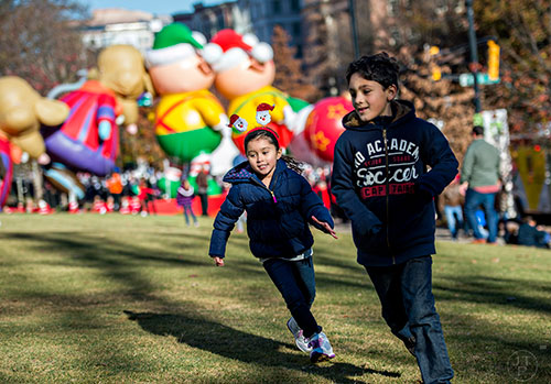Marcela Wilhelm (center) chases after her cousin Daniel Bustillos as they play tag before the start of the 2015 Children's Christmas Parade in Atlanta on Saturday, December 5, 2015. 