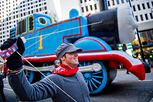 Nick Hutchens (center) holds a guide rope to the train balloon during the 2015 Children's Christmas Parade in Atlanta on Saturday, December 5, 2015. 