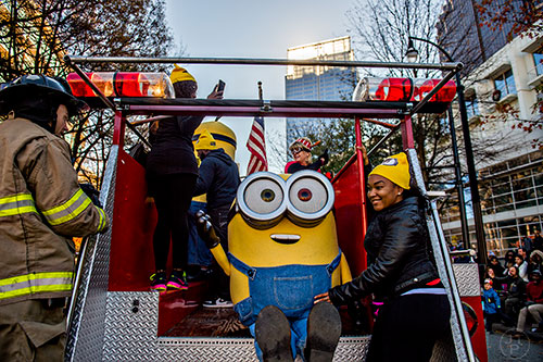 Charisma Dimuel (right) rides on a fire engine next to a minion  during the 2015 Children's Christmas Parade in Atlanta on Saturday, December 5, 2015. 