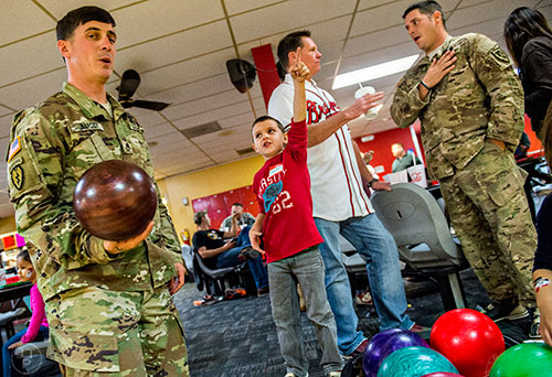 Ryan Warden (left) gets ready to bowl as he talks to Carson Lemelin as Carson's father Eric (right) talks with Atlanta Braves bullpen catcher Alan Butts during the Atlanta Braves' Military Basebowl event at Midtown Bowl in Atlanta on Saturday, December 5, 2015. 