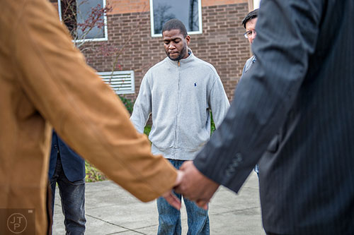 Brian Baker (center) holds hands and prays with community leaders outside of the Cobb County Police Department Headquarters in Marietta after trying to speak with Chief John R Houser on Thursday, December 10, 2015. 