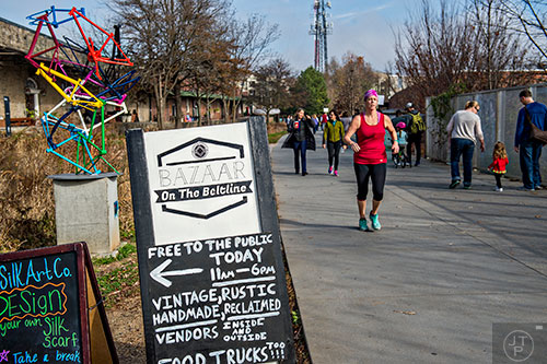 People walk, jog and bike their way down the Eastside Trail of the Atlanta Beltline as a sign entices them to check out the Bazaar on the Beltline at The Hanger on Saturday, December 12, 2015. 