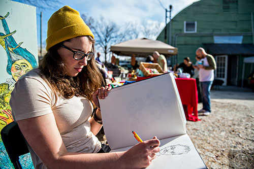Abby Witt sketches a drawing as she waits for customers during the Bazaar on the Beltline at The Hanger off of the Eastside Trail in Atlanta on Saturday, December 12, 2015. 