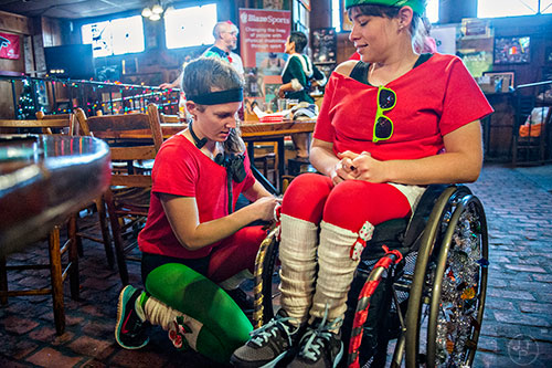 Kit McCluskey (left) helps decorate Maggie Frederick's wheelchair before the start of the annual Atlanta Santa Speedo Run at Manuel's Tavern in Atlanta on Saturday, December 12, 2015. 