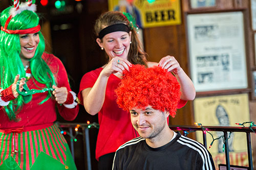 Felipe Rodrigues (right) gets help fluffing his fro from Kit McCluskey and Cynthia Frisina before the start of the annual Atlanta Santa Speedo Run at Manuel's Tavern in Atlanta on Saturday, December 12, 2015. 