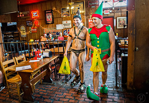 Devon McCormack (left) and Chris Campbell walk away from the registration table with their race bags before the start of the annual Atlanta Santa Speedo Run at Manuel's Tavern in Atlanta on Saturday, December 12, 2015. 