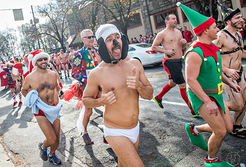 Dressed as Snoopy, Miguel Miranda (center) runs down North Highland Ave. during the annual Atlanta Santa Speedo Run at Manuel's Tavern in Atlanta on Saturday, December 12, 2015. 