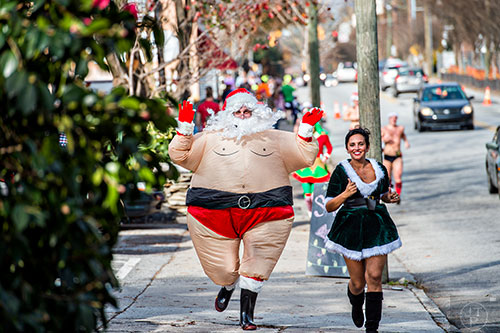 Dressed as Santa, Sean Dixon-Parker (left) and Tina Russo run up North Highland Ave. during the annual Atlanta Santa Speedo Run at Manuel's Tavern in Atlanta on Saturday, December 12, 2015. 