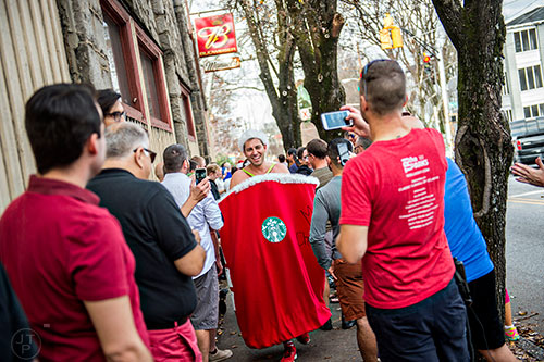 Erik Metzger (center) is greeted by onlookers as he returns to Manuel's Tavern in Atlanta at the end of the annual Atlanta Santa Speedo Run on Saturday, December 12, 2015.
