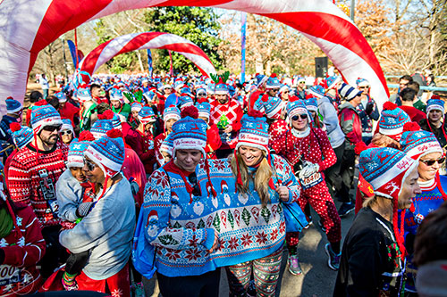 Lisa Rainey (center left) and Suzanne Smelser share a two person sweater as they wait for the start of the Ugly Sweater Run at Piedmont Park in Atlanta on Saturday, December 19, 2015. 