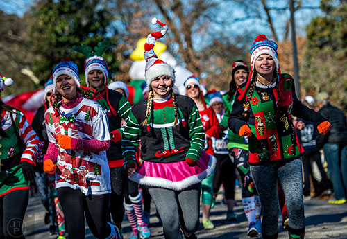 Sydney Smith (center) runs next to fiends during the Ugly Sweater Run at Piedmont Park in Atlanta on Saturday, December 19, 2015. 