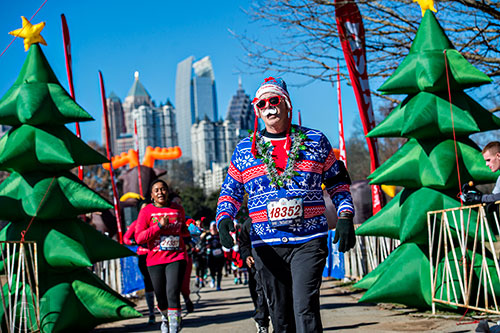 Scott Landa (right) crosses the finish line for the Ugly Sweater Run at Piedmont Park in Atlanta on Saturday, December 19, 2015. 