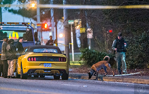 A K-9 unit searches the area around a yellow mustang after a shootout between a car jacking suspect and Atlanta Police on M.L.K. Jr. Dr. in between 285 and Brownlee Rd. in Atlanta on Monday, December 28, 2015.    