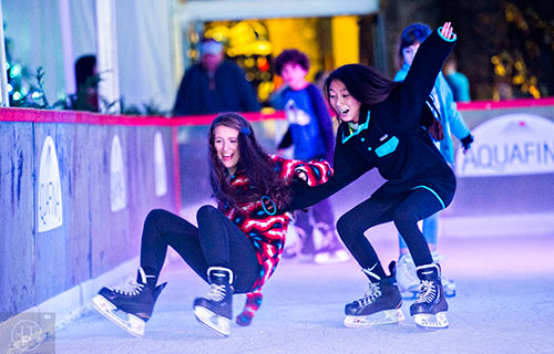 Melissa Tulgan (left) falls to the ice as she pulls her friend Teddy Oprisch with her at the Southwest Rink at Park Tavern in Atlanta on Saturday, December 26, 2015. 