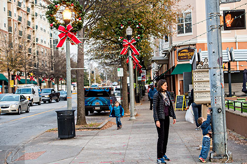 A boy presses the crosswalk button for his mother while wreaths and holiday lights decorate the light poles at the corner of Church St. and E. Ponce de Leon Ave. in Decatur.