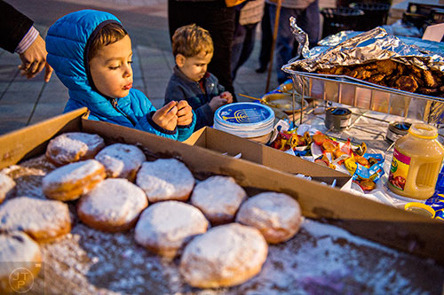 Benedict Lubell (left) and his brother Isaac move through the potato latke and jelly donut line during the Chanukah celebration in Decatur Square on Thursday.