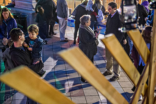 Matt Friedman (left) holds his son Jett in front of the giant menorah during the Chanukah celebration in Decatur Square on Thursday.