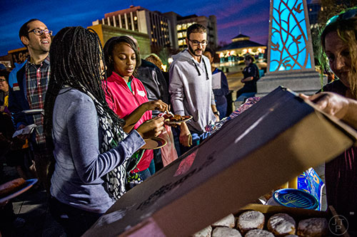 Rifqa Sa'Aadat (left) and Ashanti Aaliyah fill their plates with potato latkes during the Chanukah celebration in Decatur Square on Thursday.