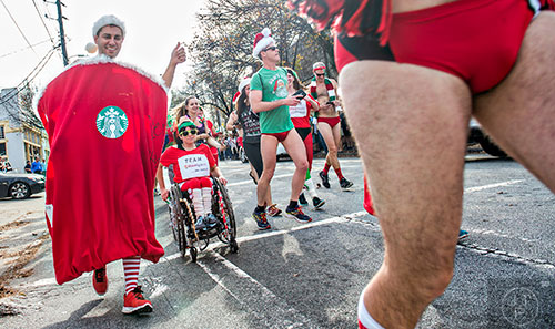 Dressed as a red Starbuck's coffee cup, Chris Campbell (left) runs down North Highland Ave. during the annual Atlanta Santa Speedo Run at Manuel's Tavern on Saturday, December 12, 2015.