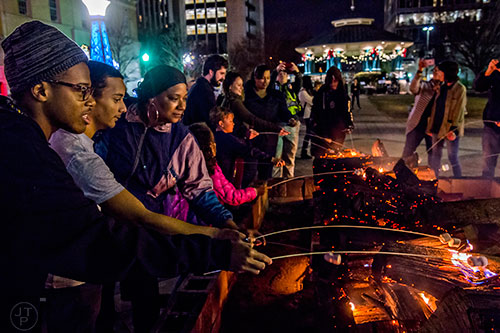 Zaylen McCoy (left), Marlon Sanchez and Lisa Beasley hold onto their sticks during the annual marshmallow roast at Decatur Square on Thursday.