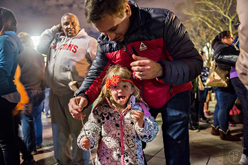 Emilia Sawyer licks marshmallow off of her lips as her father Alex leans over her during the annual marshmallow roast at Decatur Square on Thursday.
