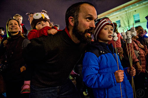 Addison Martinelli (left) holds onto her father Michael as he sing Christmas carols next to his son Aiden during the annual marshmallow roast at Decatur Square on Thursday.