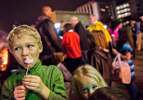 Sydney Rogers (left) eats his marshmallow off of a stick during the annual marshmallow roast at Decatur Square on Thursday.