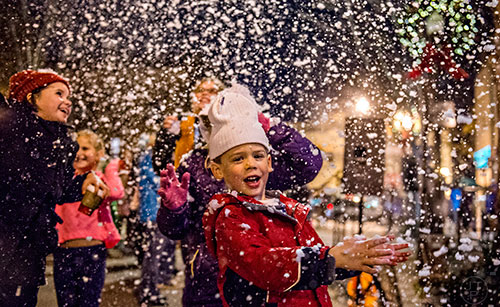 Jeremiah Hartman plays in fake snow as it falls in downtown Decatur during the annual lighting of the tree celebration on Thursday.