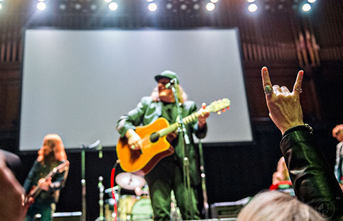 Robin Steinbrenner (right) throws up the rock n roll symbol as Kevn Kinney performs during a tribute to Alex Cooley at the Tabernacle in Atlanta on Saturday, January 9, 2016. 