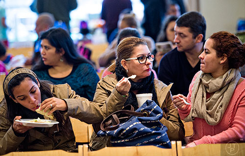 Jayra Figeroa (left), her mother Luz Acevedo and step sister Jessiree Figeroa share a sopes and a cup of elotes during the Dia de los Reyes, or Three Kings Day, celebration at the Atlanta History Center on Sunday, January 10, 2016.  