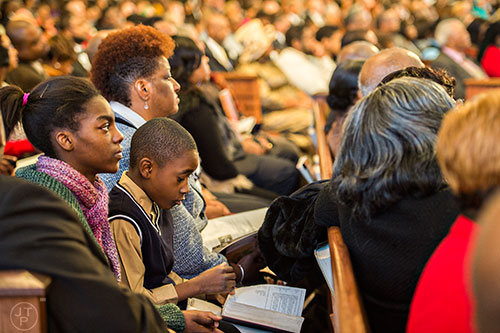 Jadan Jackson (second left) sits next to Brittany Anderson as he looks in a bible while following along with Dr. William Barber II as he quotes a passage during his speech during the 48th Martin Luther King Jr. Annual Commemorative Service at Ebenezer Baptist Church in Atlanta on Monday, January 18, 2016. 