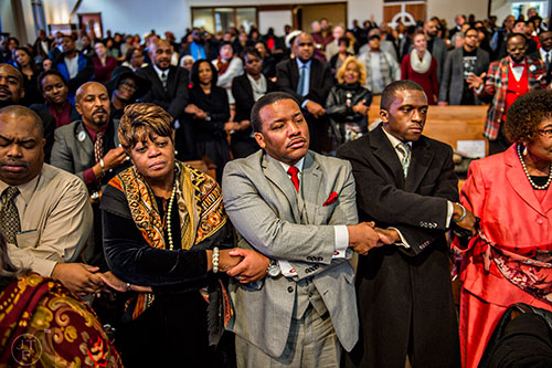 Jacqueline Lott Jackson (left) holds hands with Rev. Francis Johnson as he holds hands with J.D. Myatt while they listen to a rendition of "We Shall Overcome" during the 48th Martin Luther King Jr. Annual Commemorative Service at Ebenezer Baptist Church in Atlanta on Monday, January 18, 2016. 