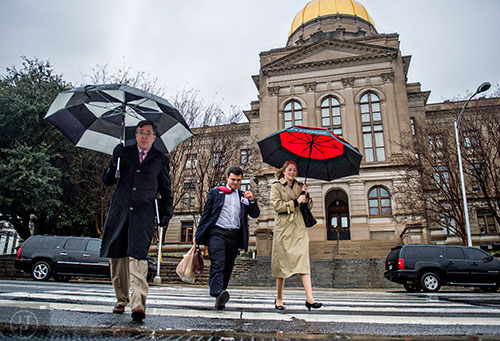 Deanna McDuffie (right) uses an umbrella to shield herself from the rain as she and others leave the state capitol building in Atlanta on Friday, January 22, 2016.