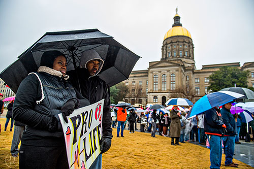 Serena Hale (left) and her husband Terrance hold a pro life sign as they listen to Pastor Mike Stone speak during a rally before the Georgia March for Life at Liberty Plaza across from the state capitol building in Atlanta on Friday, January 22, 2016. 