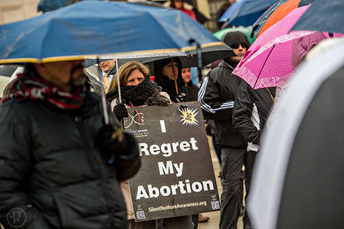 Jody Duffy (center) holds a pro life sign as she listens to Pastor Mike Stone speak during a rally before the Georgia March for Life at Liberty Plaza across from the state capitol building in Atlanta on Friday, January 22, 2016. 