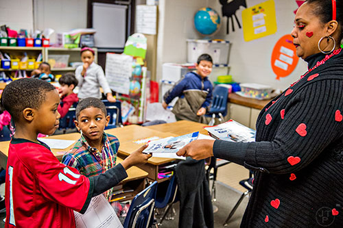 Rochelle Broughton (right) hands a book on Martin Luther King Jr. to Justin Kimbro and Daniel Cambric during her second grade class at Centerville Elementary School in Snellville on Friday, January 22, 2016. 