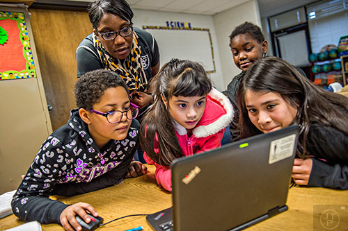 Fourth grade teacher Tremaine Carter (top left) helps Lydia Panu, Francesca Davis, Alena White and Marisol Gonzalez as they use a laptop to work on an assignment in class at Centerville Elementary School in Snellville on Friday, January 22, 2016. 