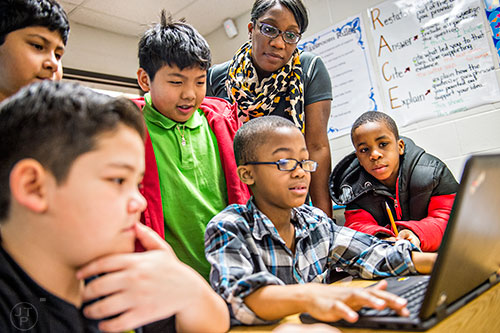 Fourth grade teacher Tremaine Carter (top right) helps Derick Figueroa, Maurilio Estrada, Tylaw Veth-Ly, Robert Cousinard and Kanye Missard as they use a laptop to work on an assignment in class at Centerville Elementary School in Snellville on Friday, January 22, 2016. 