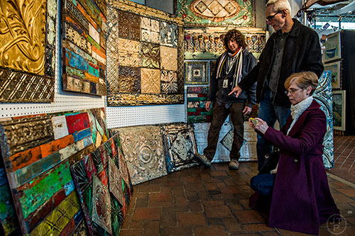 Kenny Hoff (left) talks to Larry Cox as his wife Linda takes a reference photo of one of the tin panels Hoff designs during the Callanwolde Arts Festival in Atlanta on Saturday, January 23, 2016. 