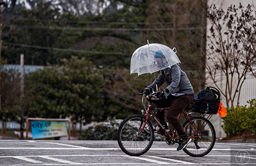 A cyclist tries to block the wind as he pedals down North Druid Hills in Atlanta on Saturday, January 23, 2016. 