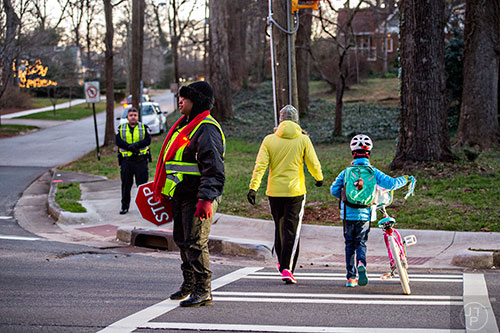 Theresa Stephens (left) stops traffic at the intersection of S. Candler St. and Kirk Rd. in Decatur so people can cross on their way to school during the Big Walk on South Candler event on Wednesday morning.