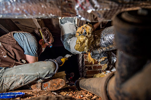 Scott Lee helps seal air conditioning ducts in the crawl space of a house during the 14th annual Martin Luther King Jr. Service Project on Sunday.