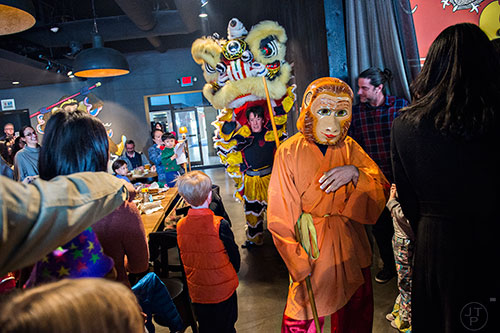Dressed as the Monkey King, Andrew Zucker leads Mary Ruth Ralston and Brian Depue through the crowd during the Lunar New Year Celebration at Makan in Decatur on Saturday, February 6, 2016. 