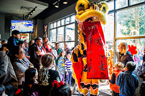 Brian Depue (bottom center) holds Mary Ruth Ralston on his shoulders as she unfurls a happy new year sign during the Lunar New Year Celebration at Makan in Decatur on Saturday, February 6, 2016. 