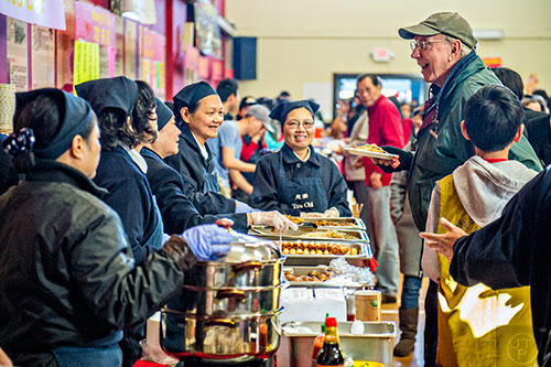 Wes Carter (right) receives a plate of food during the Atlanta Chinese Lunar New Year Festival in Chamblee on Saturday, February 13, 2016. 