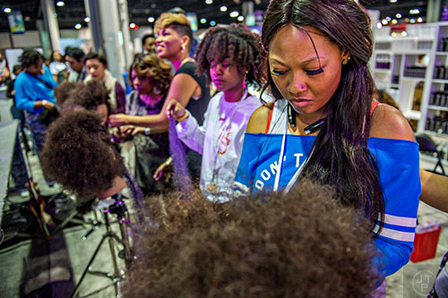 Michelle Seymour (right) practices hair styling on a dummy during the Bronner Brothers International Beauty Show at the Georgia World Congress Center in Atlanta on Saturday, February 20, 2016.
