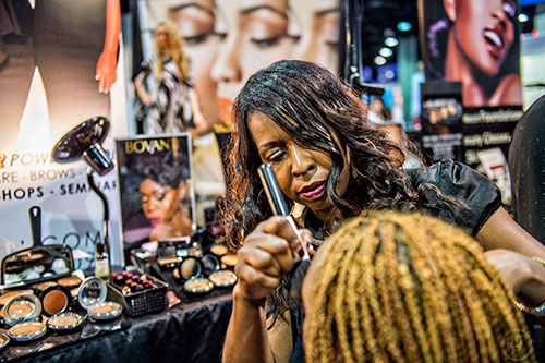 Brigitte Victoria (center) applies makeup to Patricia West's face during the Bronner Brothers International Beauty Show at the Georgia World Congress Center in Atlanta on Saturday, February 20, 2016. 