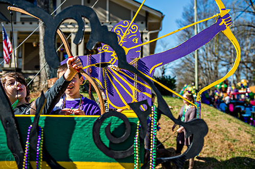 Xander Golubic (left) practices launching beads into the air with a bow before the start of the first annual LantaGras Parade in Kirkwood on Saturday.