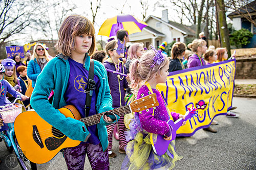 Sadie Hearsch (left) plays her guitar as she marches during the Mead Rd. Mardi Gras Parade on Saturday.